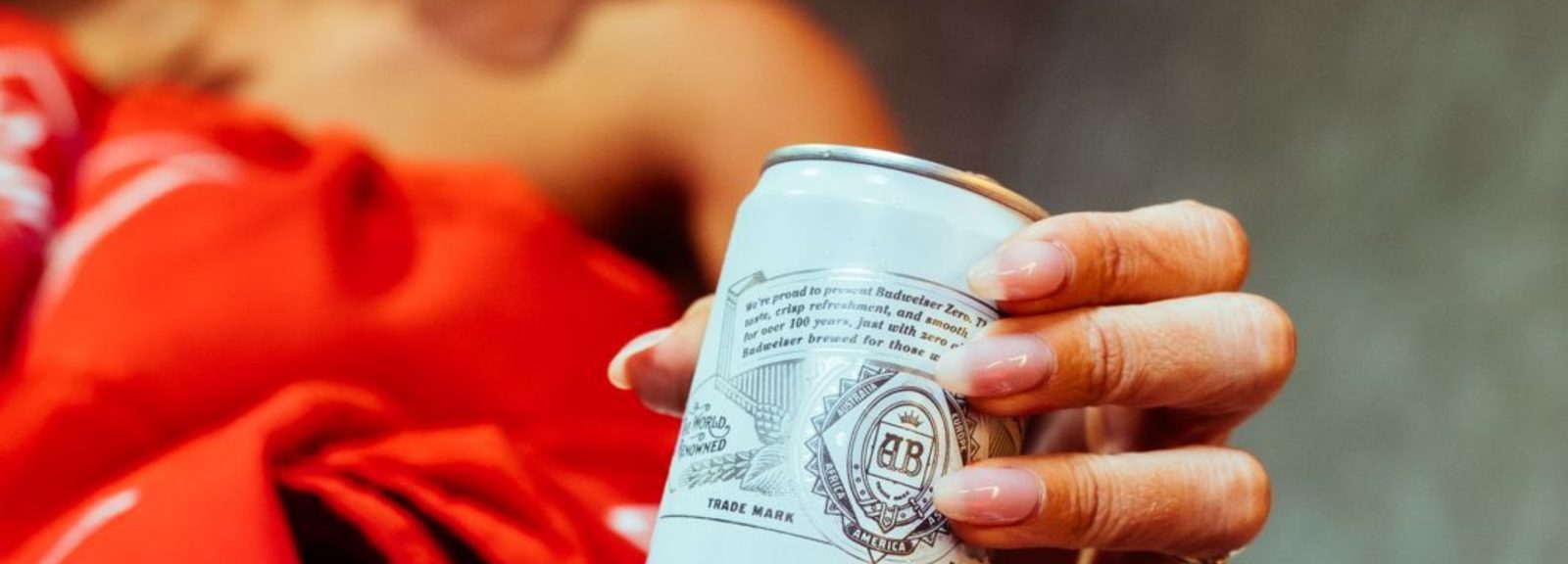 Malu Borges de vermelho segurando uma lata de Budweiser Zero